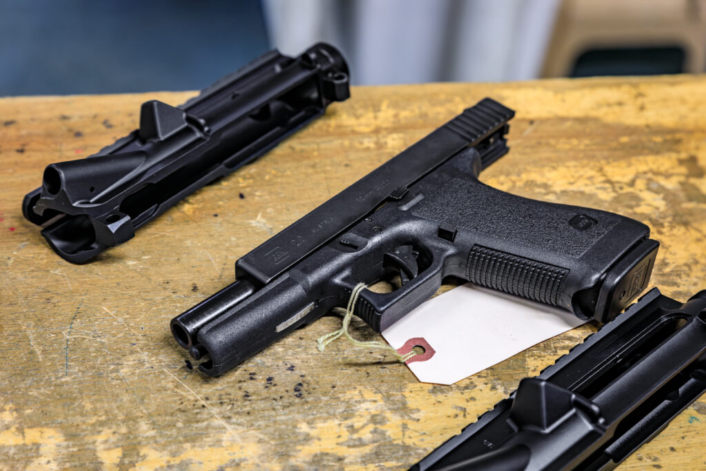 Placerville, USA - October 1, 2022: Black Glock 20 10mm caliber with a sales tag and 2 upper receivers displayed for sale at a gun shop in California