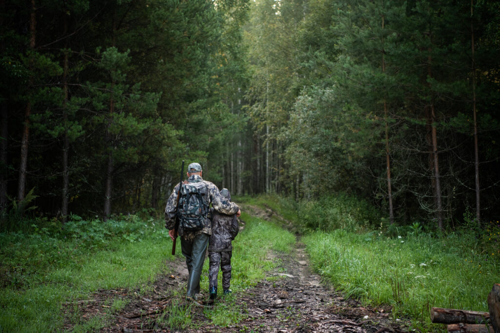 father pointing and guiding son on first deer hunt.